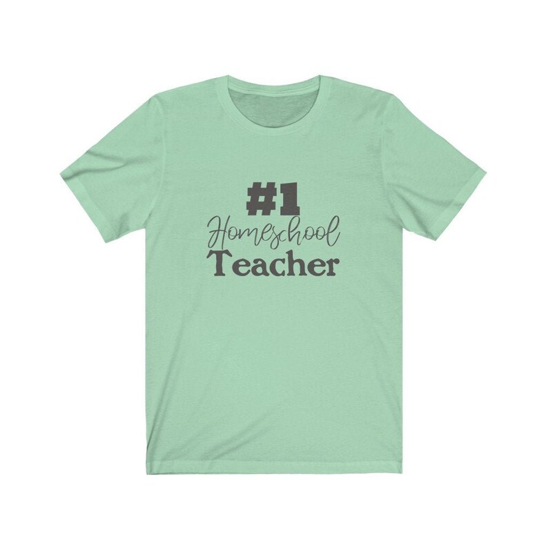 K&ouml;nnte beinhalten: Ein hellgr&uuml;nes T-Shirt mit dem Text "#1 Homeschool Teacher" in Schwarz.