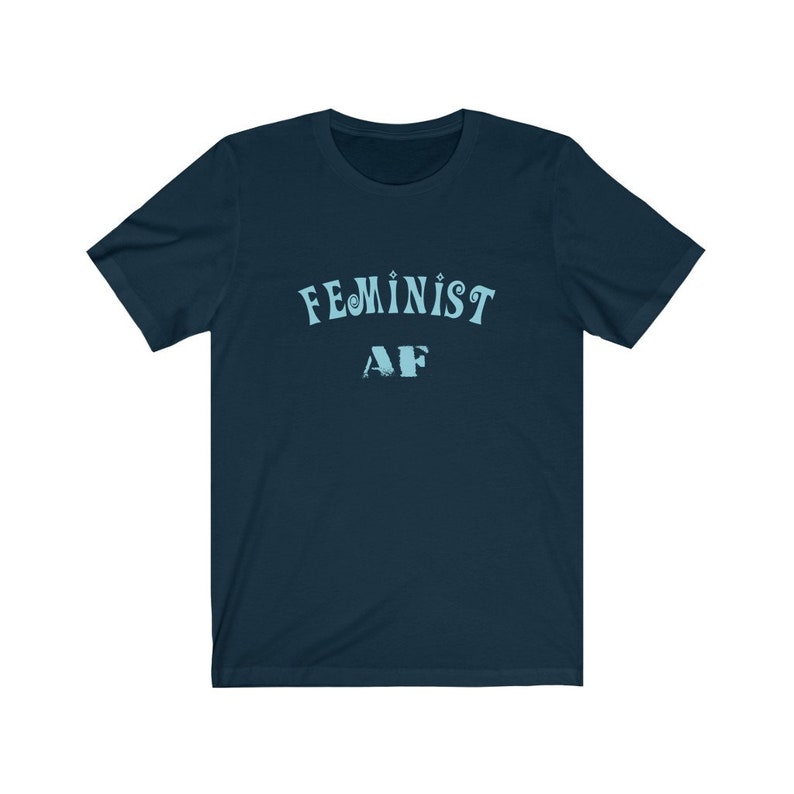 Op de afbeelding: Een marineblauw t-shirt met de tekst "FEMINIST AF" in lichtblauw.