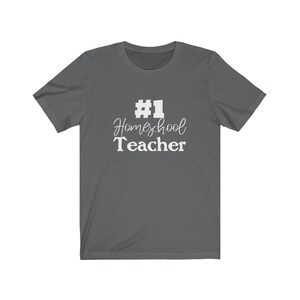 K&ouml;nnte beinhalten: Ein dunkelgraues T-Shirt mit wei&szlig;em Text, der "#1 Homeschool Teacher" lautet.