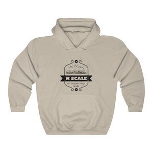 Puede incluir: Una sudadera con capucha de color beige con un gr&aacute;fico negro de un tren y el texto "N SCALE It's The Little Things In Life".