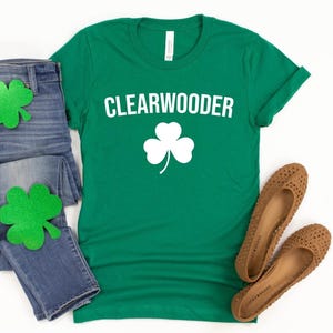 May include: Green t-shirt with white text that says "CLEARWOODER" and a white shamrock.