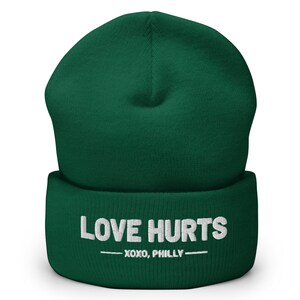 May include: A green beanie with the text "LOVE HURTS -XOXO, PHILLY-  " in white.