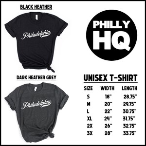 May include: Black and dark heather grey unisex t-shirts with the word "Philadelphia" in white script. The image also includes a black circle with "PHILLY HQ" in white block letters and a size chart. Widths range from 45.7 cm to 71.1 cm.