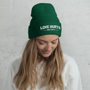 K&ouml;nnte beinhalten: Eine dunkelgr&uuml;ne M&uuml;tze mit dem in Wei&szlig; gestickten Text "LOVE HURTS - XOXO, PHILLY".