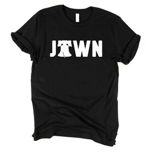 Peut inclure: T-shirt noir avec un graphique blanc de la Liberty Bell et le mot "JTOWN" imprim&eacute; sur le devant.