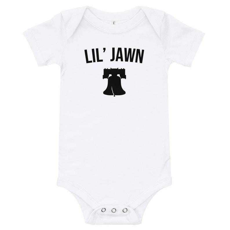May include: White baby grow with black text that reads "Lil' Jawn" and a black silhouette of the Liberty Bell.