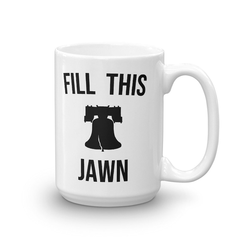 Puede incluir: Taza de cer&aacute;mica blanca con una silueta negra de la Campana de la Libertad y el texto "FILL THIS JAWN".