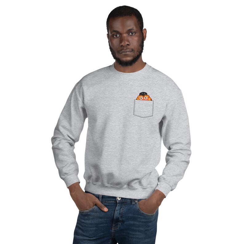 May include: A gray sweatshirt with a front pocket featuring a cartoon monster peeking out. The monster is orange with black eyes and a black hat.