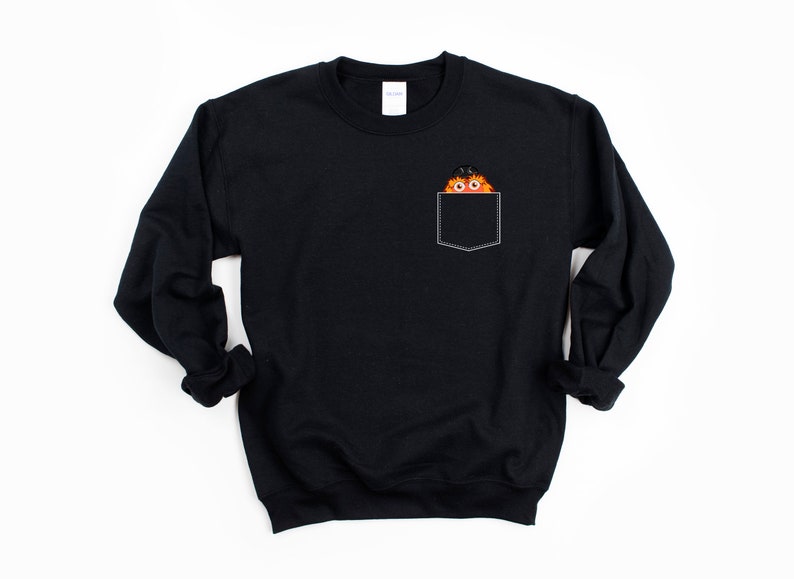 May include: Black sweatshirt with a pocket featuring a cartoon character with orange fur and a black hat peeking out of the pocket.