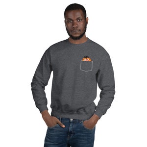 May include: A dark gray sweatshirt with a front pocket. A cartoon character with orange fur and a black hat is peeking out of the pocket.