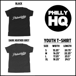 May include: Black and dark heather grey youth t-shirts with the word "Philadelphia" in white script. A black circle with "PHILLY HQ" in white is also shown. Size chart includes width and length in inches.