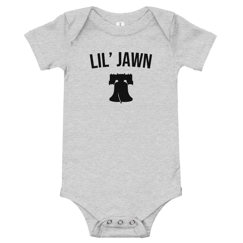 May include: A grey baby grow with black text that reads "Lil' Jawn" and a black silhouette of the Liberty Bell.