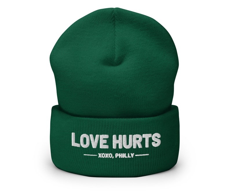 May include: A green beanie with the text "LOVE HURTS -XOXO, PHILLY-  " in white.