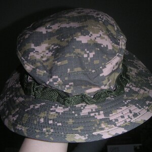 May include: A camouflage-patterned boonie hat with a green drawstring.