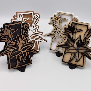 May include: Four wooden decorative wall hangings featuring a lily flower design. Two of the hangings have a white lily design on a brown background, and two have a black lily design on a white background.