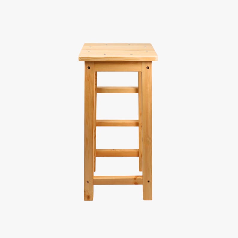 May include: A natural wood stool with a square top and three horizontal supports. The stool is made of light-colored wood and has a simple, functional design. The stool is suitable for various uses.