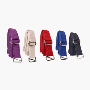 May include: Five fabric belts with metal buckles in different colors: purple, white, red, blue, and black.