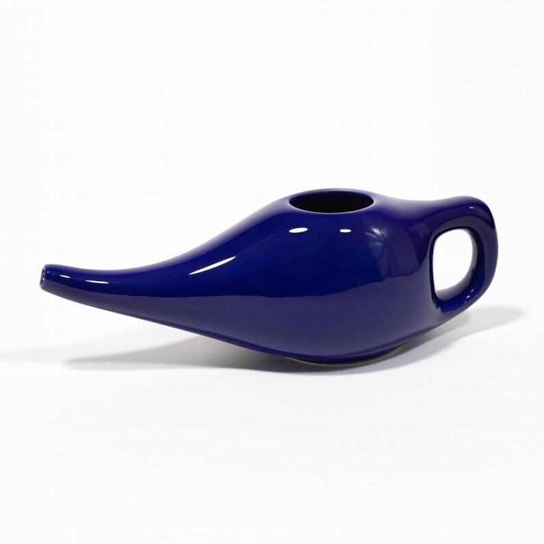 Puede incluir: Una olla neti de cer&aacute;mica azul cobalto con una boquilla larga y un asa. La olla tiene un acabado liso y brillante y una base redondeada. La abertura es circular.