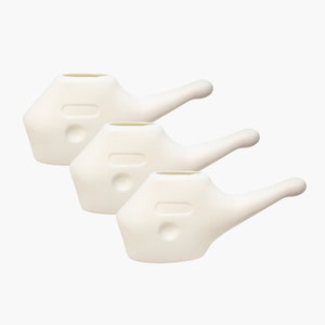 Op de afbeelding: Drie witte plastic neusdouches met een tuit en een handvat. De douches zijn op elkaar gestapeld.