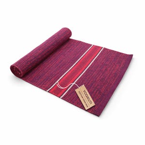May include: A rolled-up, burgundy cotton yoga rug with red and white stripes. The rug has a woven texture and a rectangular shape. A small, rectangular tag with the text "YOGIKUTI COTTON YOGA RUG" is attached to the rug.