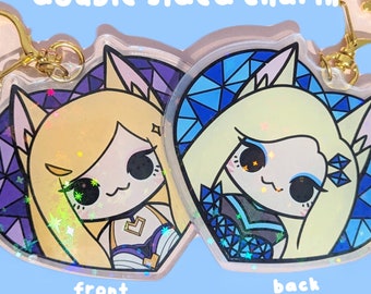 May include: Double-sided charm featuring a cartoon character with blonde hair and blue eyes. The front side has a purple and blue background with stars and the character is wearing a blue and white outfit. The back side has a blue and white background with a geometric pattern and the character is wearing a blue and black outfit.