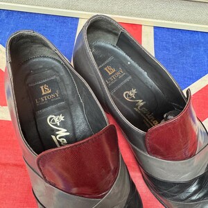 K&ouml;nnte beinhalten: Ein Paar Vintage-Lederschuhe mit Colorblock-Design. Die Schuhe haben eine weinrote Kappe, graue und schwarze Akzente, und der Markenname "L'STONY" ist auf der Innensohle sichtbar.