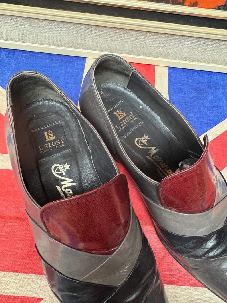 K&ouml;nnte beinhalten: Ein Paar Vintage-Lederschuhe mit Colorblock-Design. Die Schuhe haben eine weinrote Kappe, graue und schwarze Akzente, und der Markenname "L'STONY" ist auf der Innensohle sichtbar.