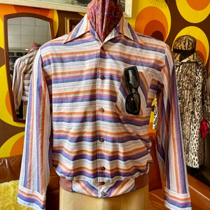 May include: A striped long-sleeve shirt with a button-up collar and a brown elastic waistband. The shirt has orange, purple, and blue stripes on a white background.