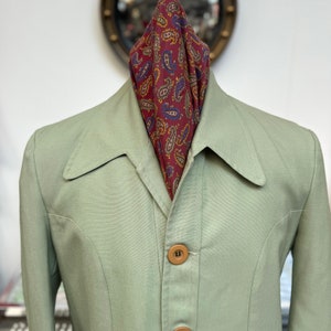 Könnte beinhalten: Ein hellgrüner Blazer mit einem Paisley-Muster-Schal. Der Blazer hat einen Kragen und drei Knöpfe auf der Vorderseite.