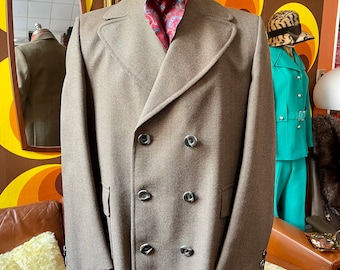 May include: A brown double-breasted peacoat with five buttons. The coat has a long, straight cut and is made of a textured fabric.