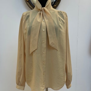 Vintage 1970s/80s Women’s Honey Pale Yellow Pussybow neck long-sleeve cuffed secretary blouse,pleated from the shoulders.Small to medium8-12