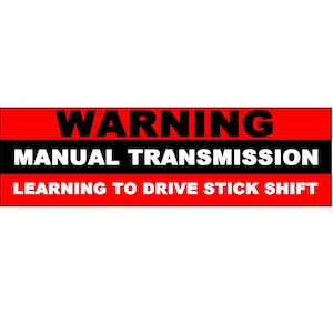 Pode incluir: Um sinal de advertência vermelho e preto com o texto "WARNING MANUAL TRANSMISSION LEARNING TO DRIVE STICK SHIFT".