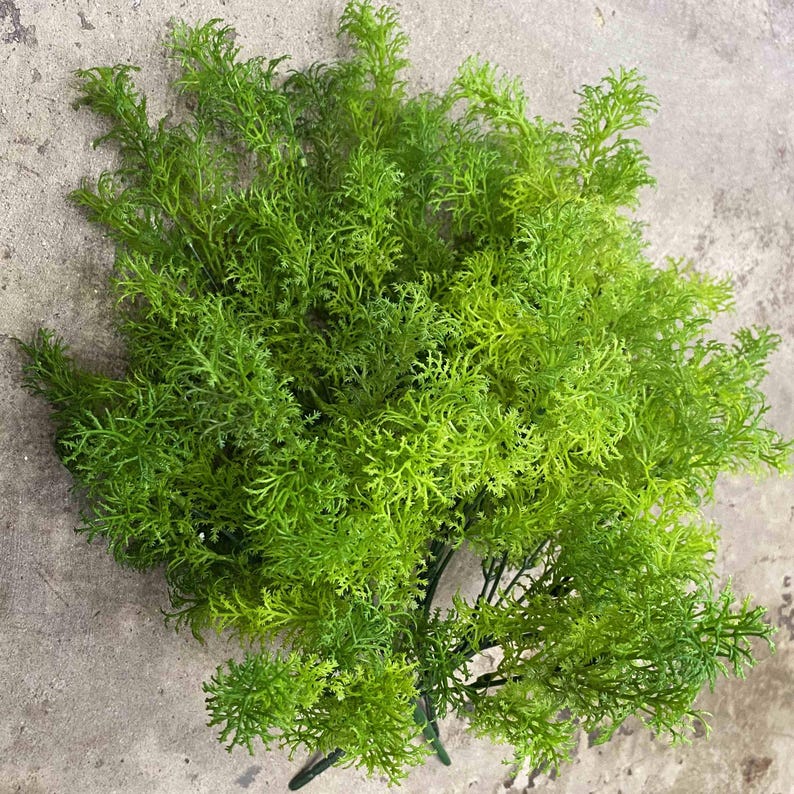 May include: A bunch of green artificial greenery sprigs. The sprigs are made of a soft, feathery material and are perfect for adding a touch of nature to any space.