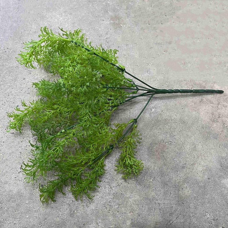 May include: A bunch of artificial green ferns with wire stems. The ferns are arranged in a cluster and have a natural, realistic look.
