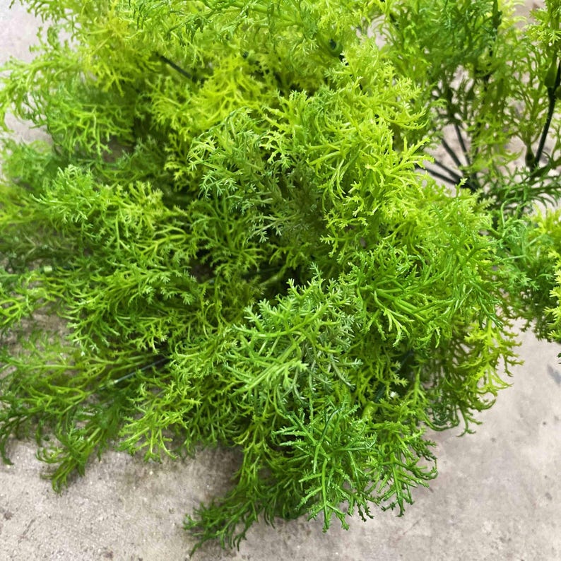 May include: A bunch of green artificial greenery with long, thin leaves. The greenery is perfect for adding a touch of nature to any space.
