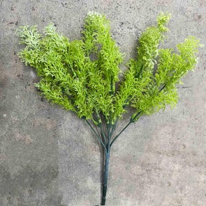 May include: A bunch of artificial green leafy sprigs with a long stem. The sprigs are arranged in a bouquet shape.
