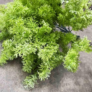 May include: A bunch of green artificial greenery with a feathery texture. The greenery is perfect for adding a touch of nature to any space.