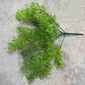 May include: A bunch of artificial green fern sprigs with a wire stem. The sprigs are arranged in a fan shape and have a delicate, feathery texture.