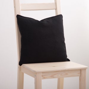 Black linen pillow case on a chair.