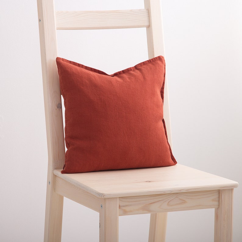 Burnt orange decorative square pillow case on a chair.