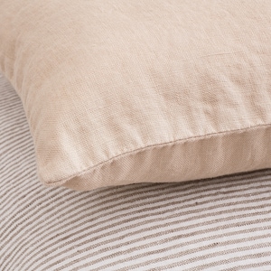 May include: Two beige linen pillow covers, one with a subtle striped pattern and the other with a smooth texture.
