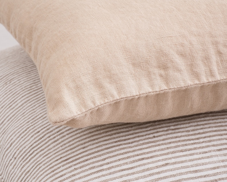May include: Two beige linen pillow covers, one with a subtle striped pattern and the other with a smooth texture.