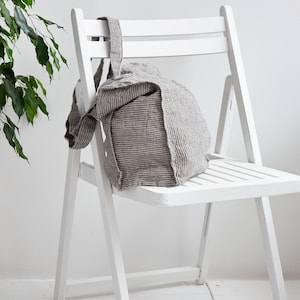 May include: A white folding chair with a striped linen tote bag sitting on the seat.