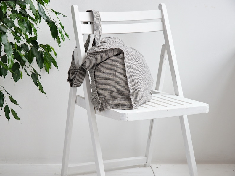 May include: A white folding chair with a striped linen tote bag sitting on the seat.