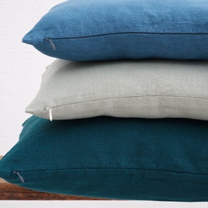 Stacked deocorative square pillow covers, in the colors denim blue, mint and dark teal with a hidden zipper closure.