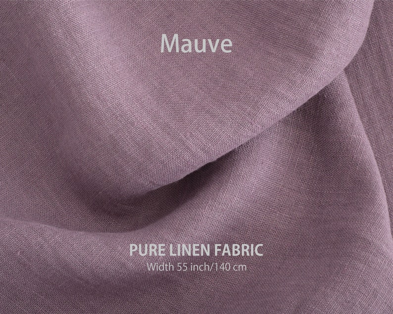 May include: Mauve coloured pure linen fabric. The fabric is folded and has a soft, textured appearance. The fabric is 55 inches wide or 140 cm.