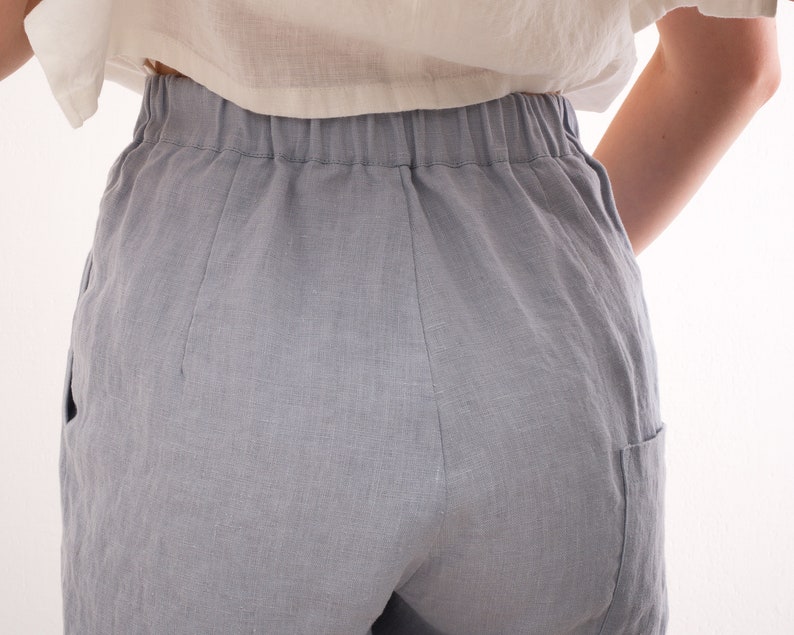 May include: Light blue linen shorts with an elastic waistband and side pockets. The shorts are made of a soft, breathable fabric, perfect for warm weather. The shorts are shown from the back.