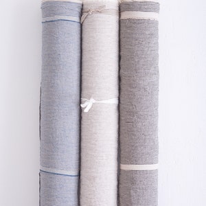 May include: Three rolls of striped fabric, one blue and white, one beige and white, and one gray and white.