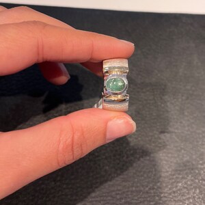 Op de afbeelding: Een zilveren ring met een groene ovale edelsteen in het midden. De ring heeft een getextureerde band.