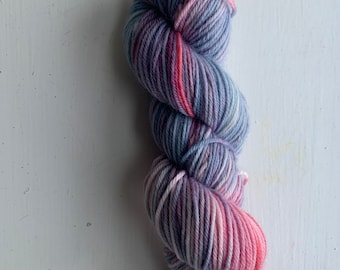 May include: A skein of yarn in shades of pink, blue, and white. The yarn is twisted into a spiral shape.